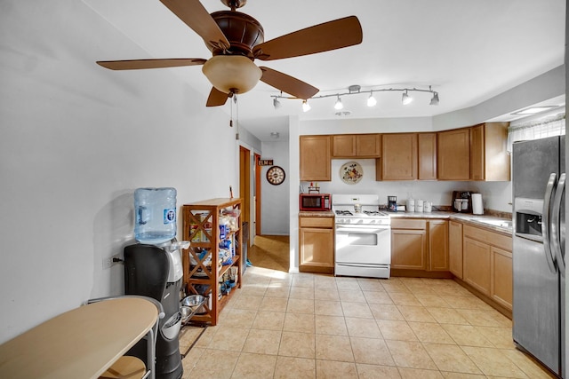 kitchen with white range with gas stovetop, stainless steel fridge with ice dispenser, light tile patterned floors, and ceiling fan