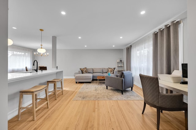 living room featuring a chandelier, sink, and light hardwood / wood-style flooring