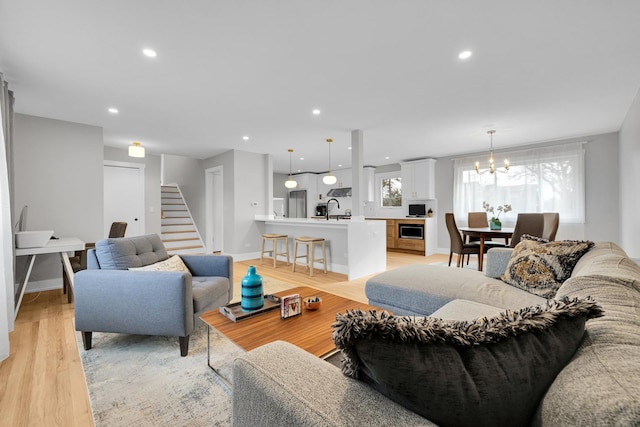 living room featuring light hardwood / wood-style flooring, a chandelier, plenty of natural light, and sink