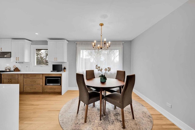 dining area with light hardwood / wood-style flooring and a notable chandelier