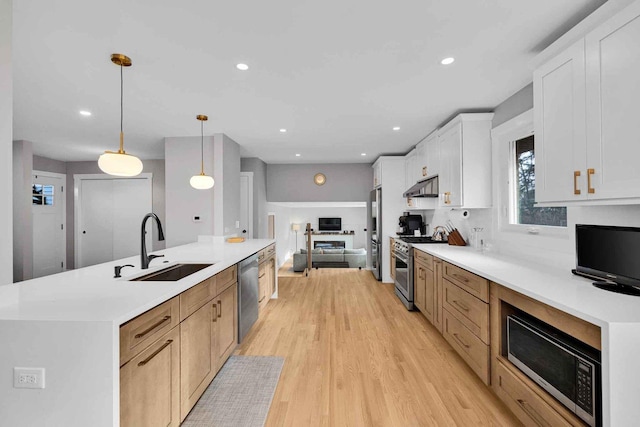 kitchen with light brown cabinets, stainless steel appliances, a large island with sink, pendant lighting, and white cabinets