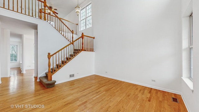 unfurnished living room with an inviting chandelier, hardwood / wood-style flooring, and a high ceiling