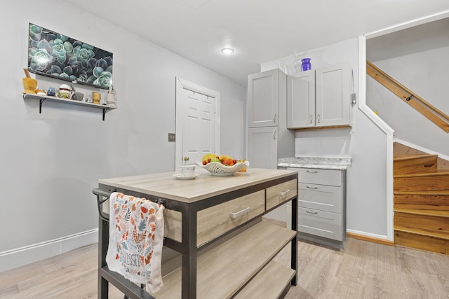 kitchen with gray cabinets, baseboards, light countertops, and light wood finished floors