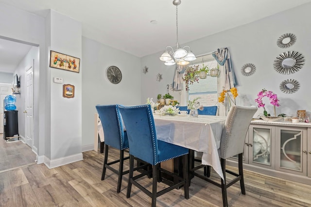 dining area featuring a notable chandelier, baseboards, and wood finished floors