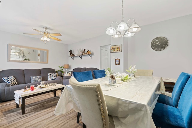 dining area featuring ceiling fan with notable chandelier and wood finished floors