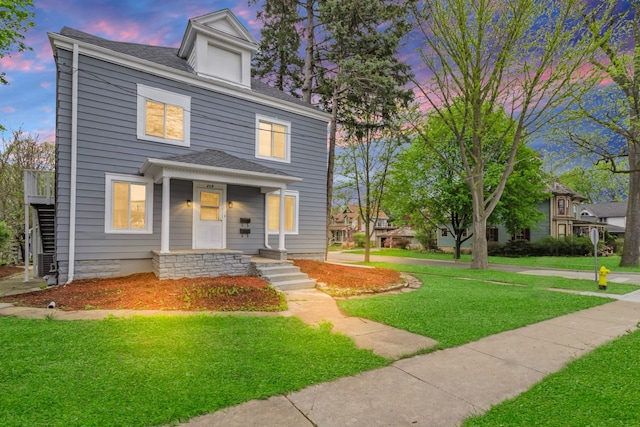 view of front of property with covered porch, stairway, and a front yard