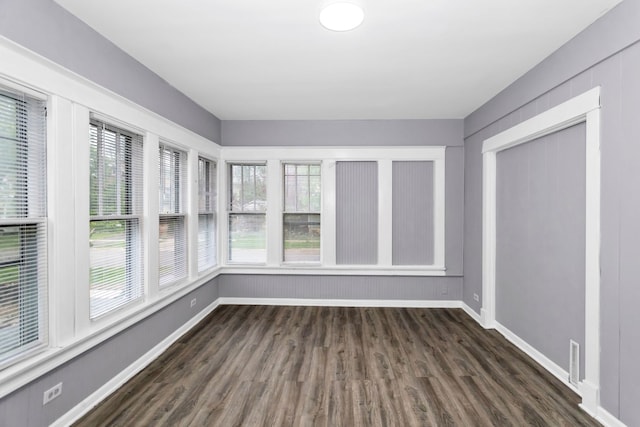 unfurnished sunroom featuring baseboards, wood finished floors, and visible vents
