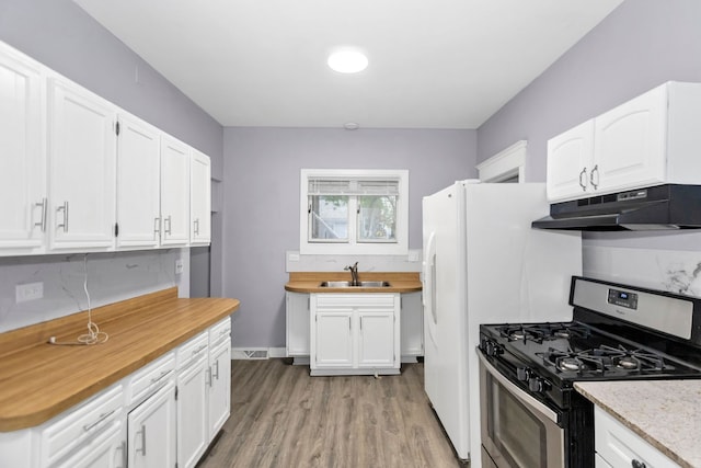 kitchen with stainless steel gas range oven, a sink, white cabinets, under cabinet range hood, and light wood-style flooring