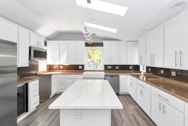 6N772 Tuscola Ave, Saint Charles, IL 60174 - kitchen featuring appliances with stainless steel finishes, a sink, a skylight, light wood-type flooring, and vaulted ceiling