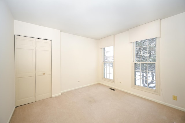 unfurnished bedroom with a closet and light carpet