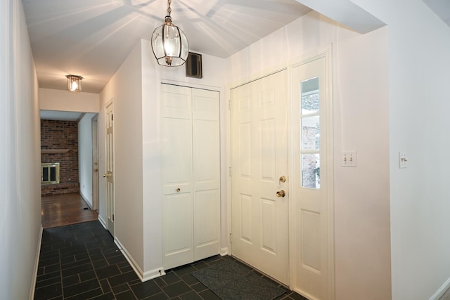 entryway featuring dark tile patterned floors and a brick fireplace