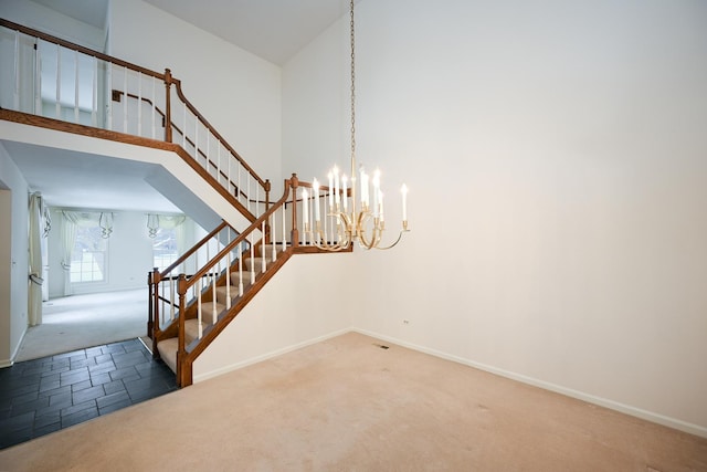 stairway with a towering ceiling, a chandelier, and carpet