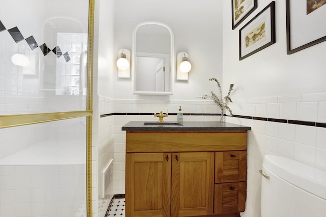 bathroom with toilet, vanity, and tile walls