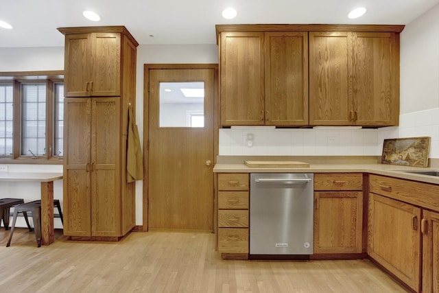 kitchen with stainless steel dishwasher, light hardwood / wood-style floors, and decorative backsplash