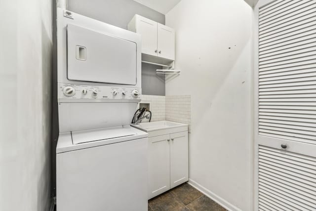 washroom featuring cabinets, stacked washer / drying machine, and sink