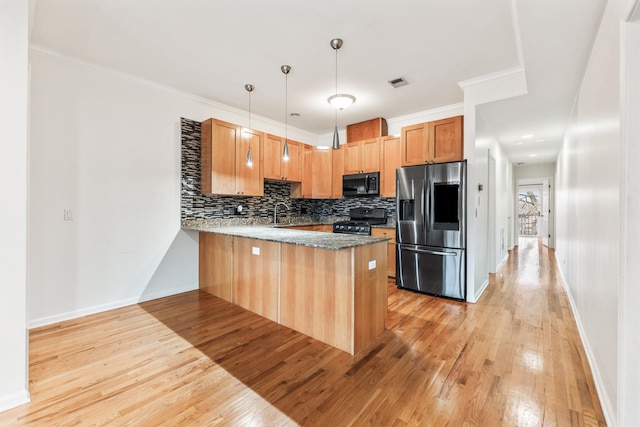 kitchen featuring hanging light fixtures, backsplash, kitchen peninsula, black appliances, and light wood-type flooring