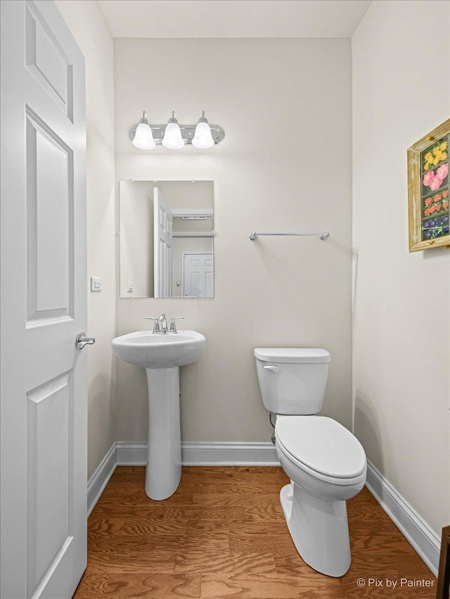 bathroom with wood-type flooring, toilet, and sink