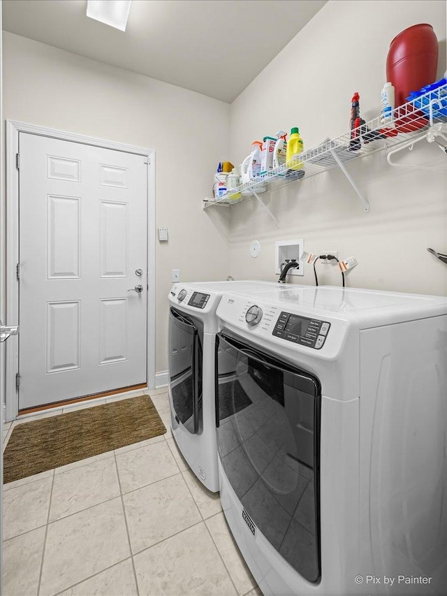 clothes washing area with washing machine and dryer and light tile patterned floors