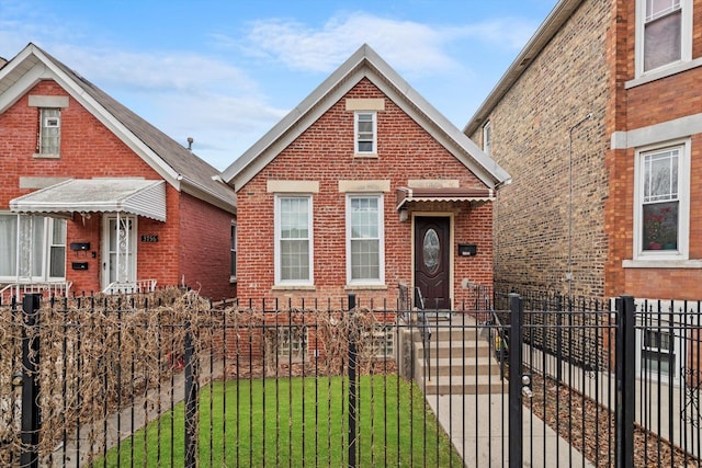 view of front of property with a fenced front yard, a gate, brick siding, and a front lawn