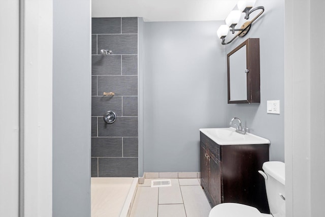 bathroom with visible vents, tiled shower, toilet, tile patterned flooring, and vanity