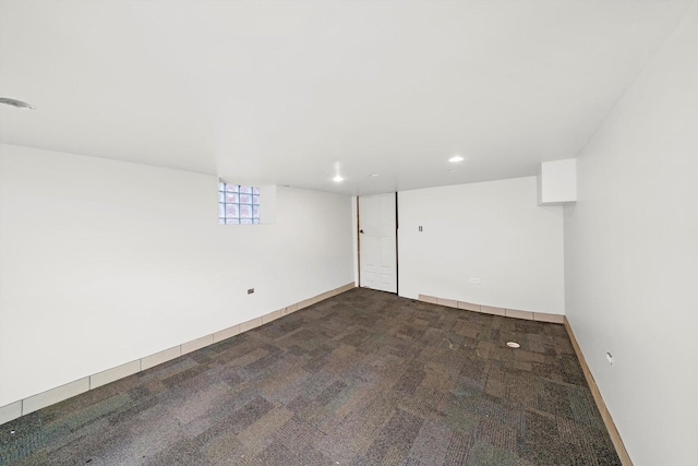 basement featuring dark colored carpet, baseboards, and recessed lighting