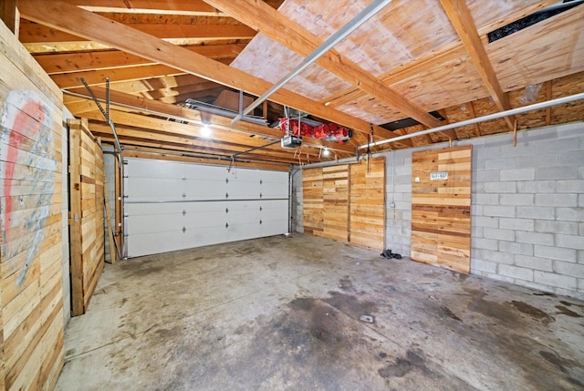 garage featuring concrete block wall and a garage door opener