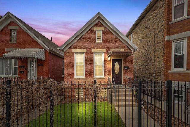 view of front of home with brick siding, a fenced front yard, and a front lawn