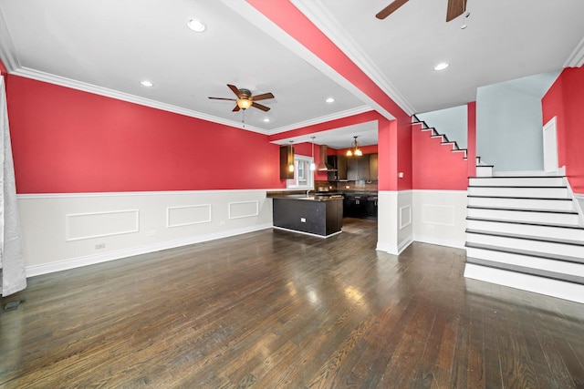 unfurnished living room featuring a wainscoted wall, stairway, a ceiling fan, and ornamental molding