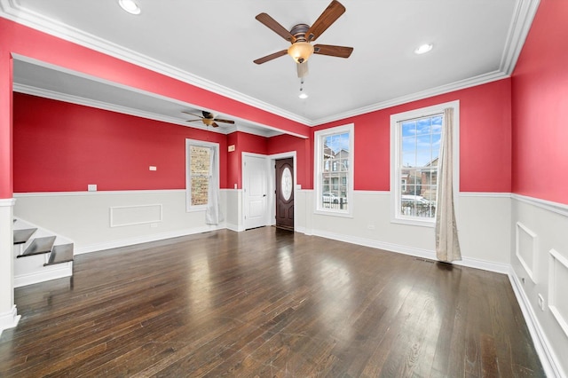 unfurnished room with wainscoting, hardwood / wood-style flooring, ceiling fan, ornamental molding, and stairs