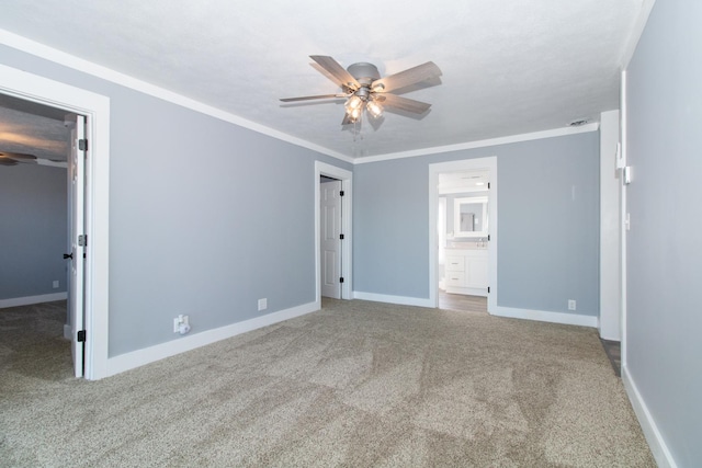 unfurnished bedroom with ceiling fan, ornamental molding, carpet flooring, and ensuite bath