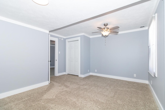 unfurnished room with ceiling fan, light colored carpet, and crown molding