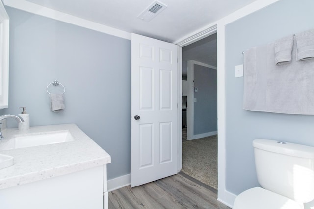 bathroom featuring toilet, vanity, and wood-type flooring