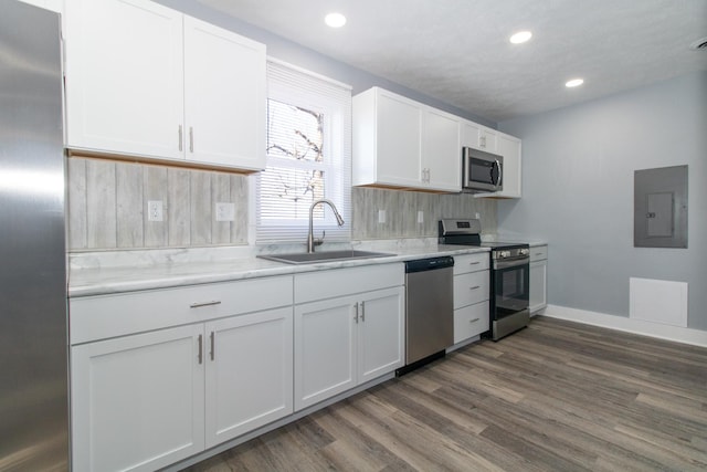 kitchen featuring stainless steel appliances, decorative backsplash, electric panel, white cabinets, and sink