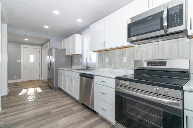 kitchen with white cabinets, backsplash, sink, and stainless steel appliances