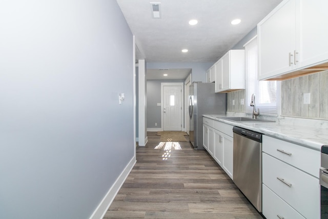 kitchen with stainless steel dishwasher, white cabinets, light stone counters, and sink