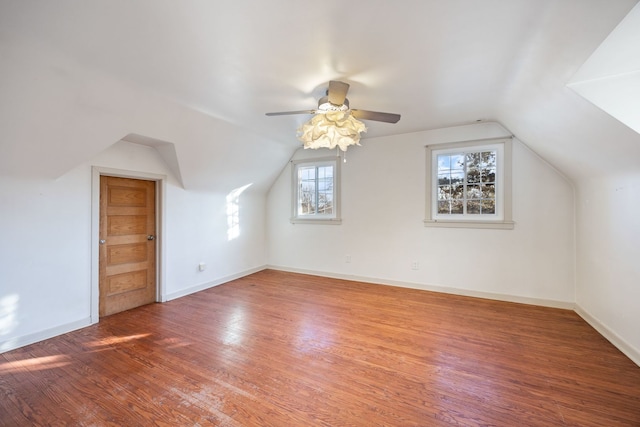 additional living space with hardwood / wood-style floors, a healthy amount of sunlight, and vaulted ceiling