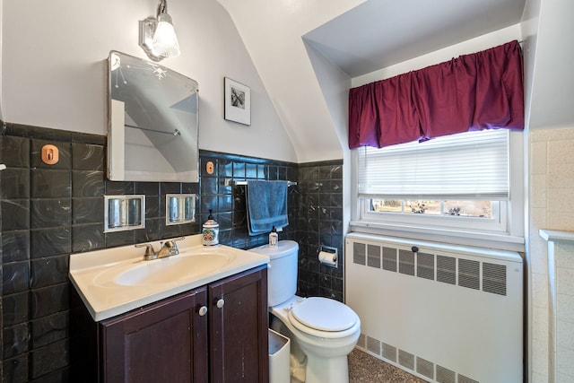 bathroom featuring radiator heating unit, vanity, vaulted ceiling, and tile walls