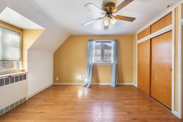 additional living space with light hardwood / wood-style floors, radiator, lofted ceiling, and ceiling fan