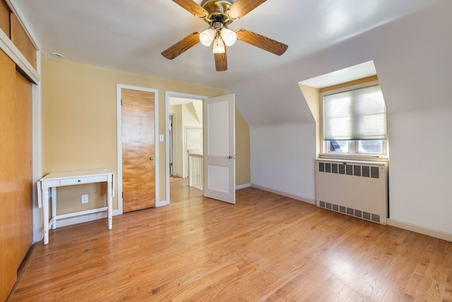 bonus room with light wood-type flooring, ceiling fan, radiator heating unit, and lofted ceiling