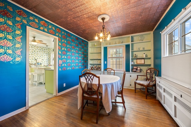 dining space featuring a notable chandelier, radiator, hardwood / wood-style floors, built in features, and brick ceiling