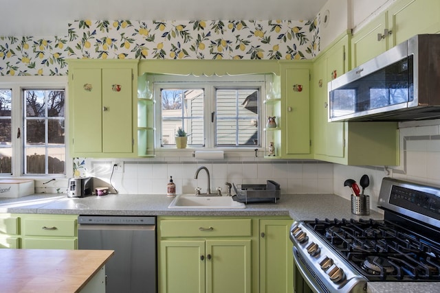 kitchen with sink, stainless steel appliances, green cabinetry, and decorative backsplash