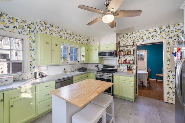 kitchen with appliances with stainless steel finishes, tasteful backsplash, sink, green cabinetry, and light tile patterned floors