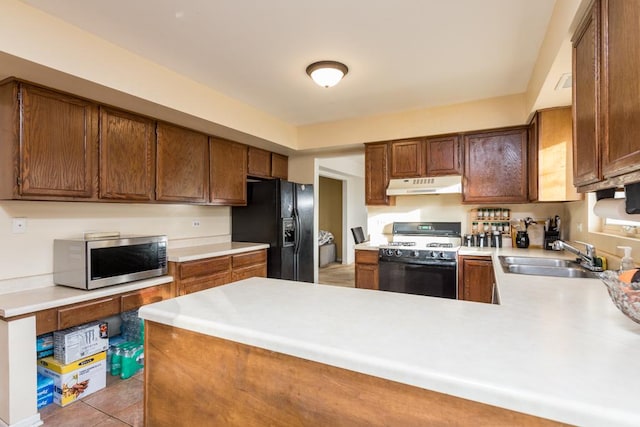 kitchen with kitchen peninsula, sink, light tile patterned floors, and black appliances