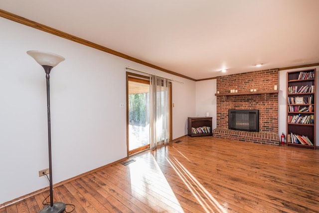 unfurnished living room featuring hardwood / wood-style floors, ornamental molding, and a brick fireplace