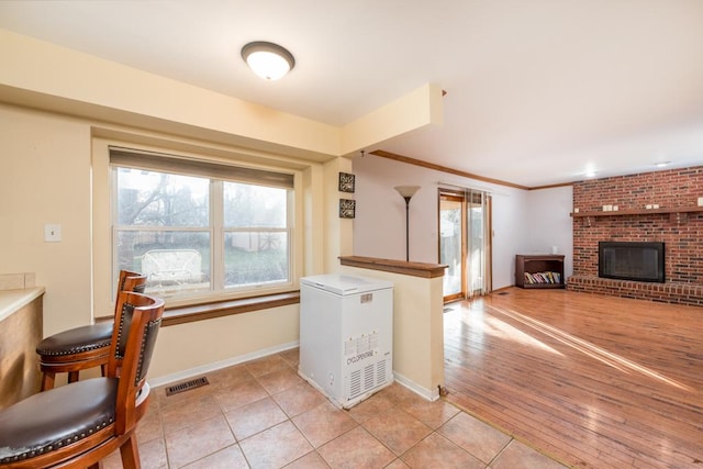 tiled living room featuring ornamental molding and a fireplace