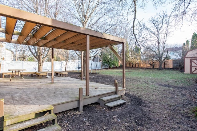 view of yard featuring a shed, a trampoline, and a deck