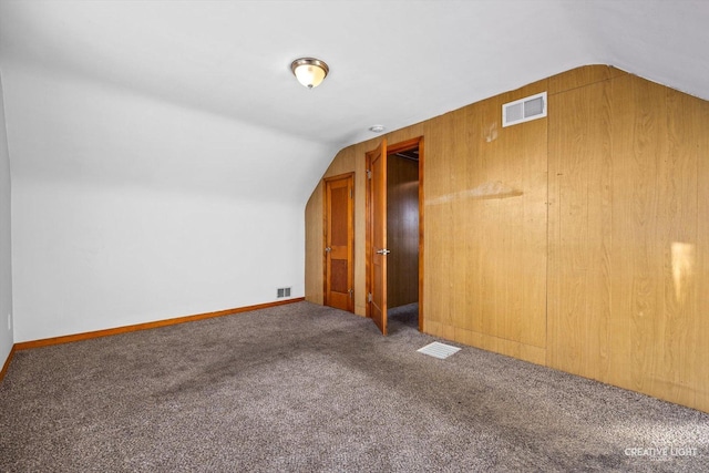 bonus room with carpet floors, vaulted ceiling, and wood walls