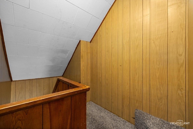 interior space featuring lofted ceiling, wooden walls, and carpet