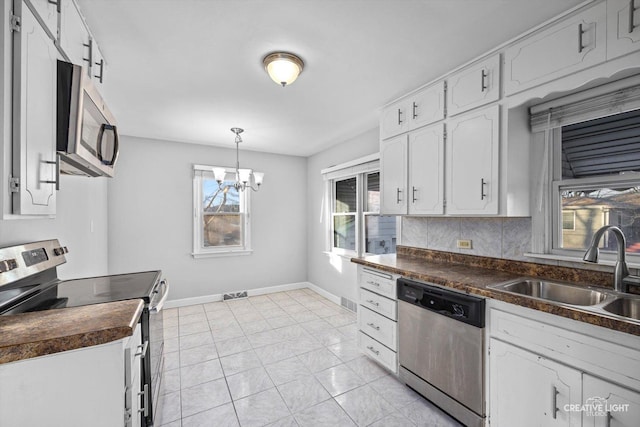 kitchen with sink, white cabinetry, an inviting chandelier, appliances with stainless steel finishes, and pendant lighting