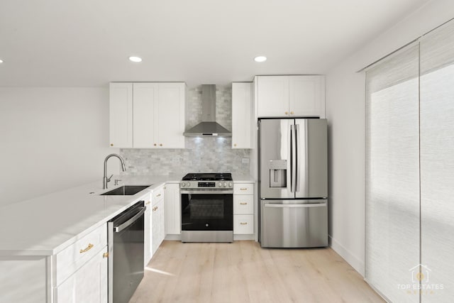 kitchen featuring sink, white cabinets, stainless steel appliances, and wall chimney range hood